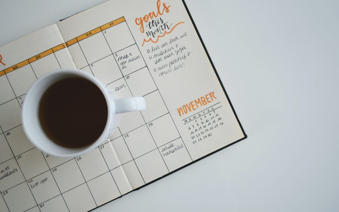 Coffee and calendar with monthly goals written out for growth